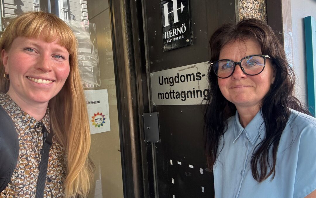 RCV:s utvecklingssamordnare Elsa Sjögren och Anna-Karin Åberg framför en skylt för ungdomsmottagningen.