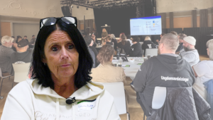 Porträttbild på en kvinna i förgrunden med konferensdeltagare i bakgrunden.