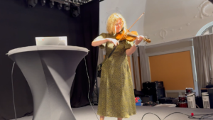 Kvinna på en scen spelar fiol, hon är moderator för Fritidsledarkonferensen i Sundsvall.